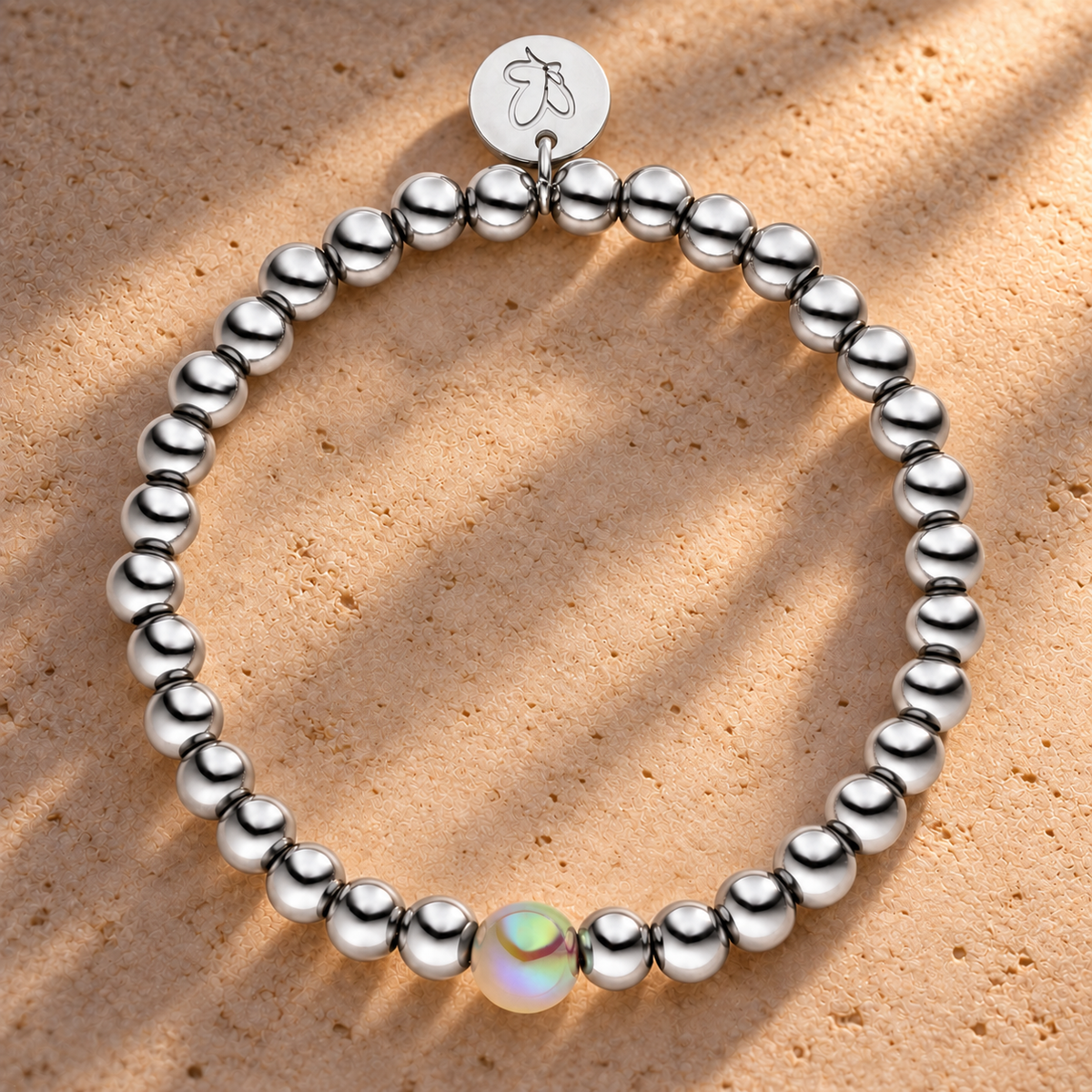 Perlenarmband Versilbert Fine Hellgrau mit 3D Intensiv Glow Effekt 6mm – auf champagnerfarbenem Hintergrund im warmen Abendlicht.