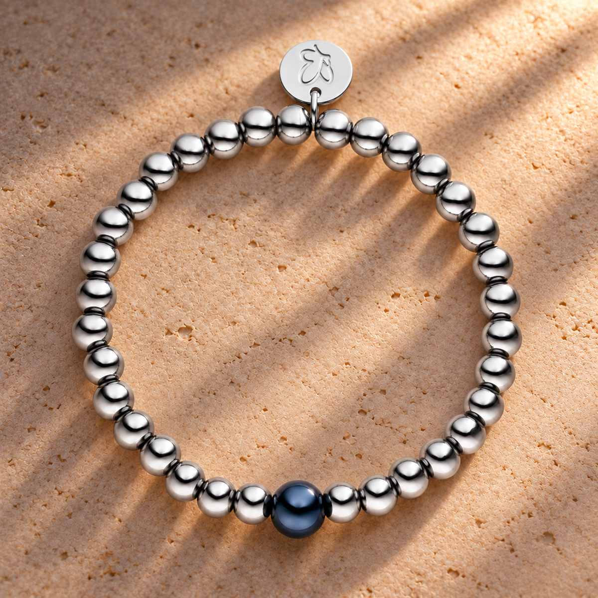 Perlenarmband Versilbert Fine Schwarz mit 3D Intensiv Glow Effekt 6mm – auf champagnerfarbenem Hintergrund im warmen Abendlicht.