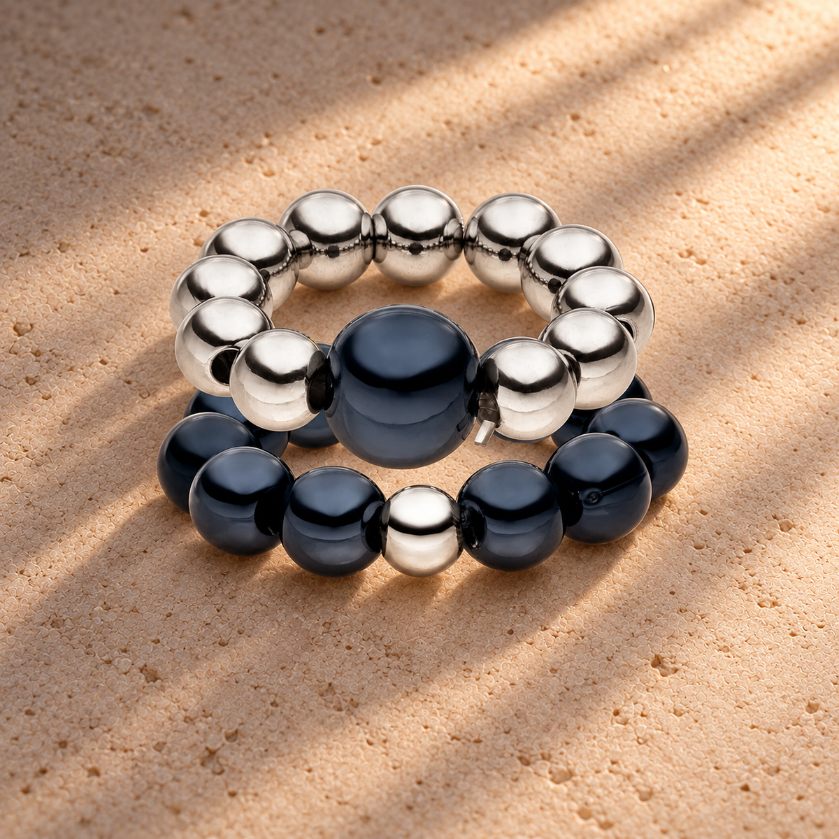 Perlenring Set 14K Versilbert Schwarz mit 3D Intensiv Glow Effekt – auf champagnerfarbenem Hintergrund im warmen Abendlicht.