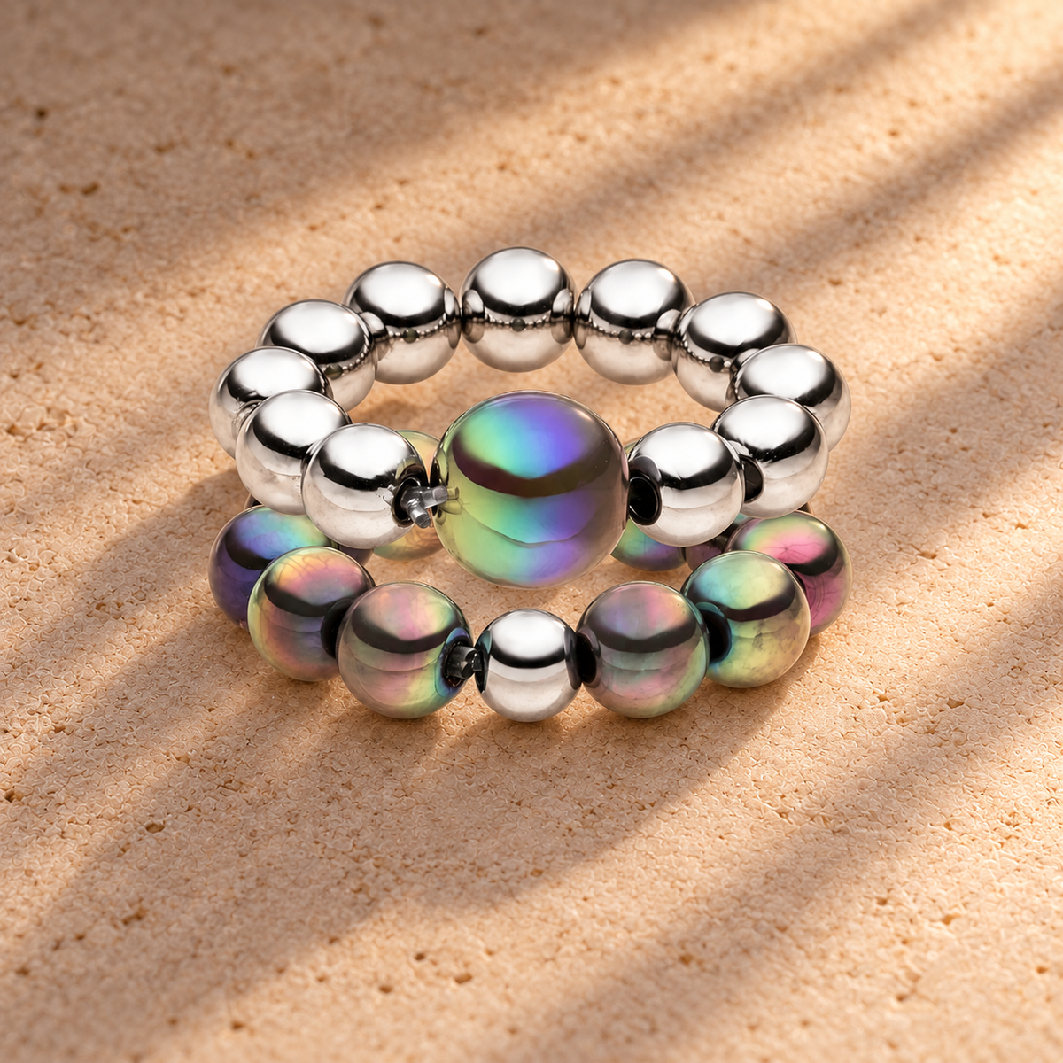Perlenring Set 14K Versilbert Dunkelgrau mit 3D Intensiv Glow Effekt – auf champagnerfarbenem Hintergrund im warmen Abendlicht.