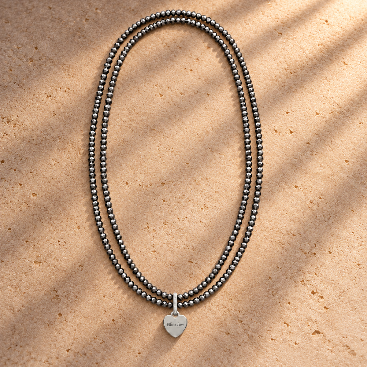 Perlenhalskette Silber mit Herz-Charm – wasserfest, 110 cm – auf champagnerfarbenem Hintergrund im warmen Abendlicht.